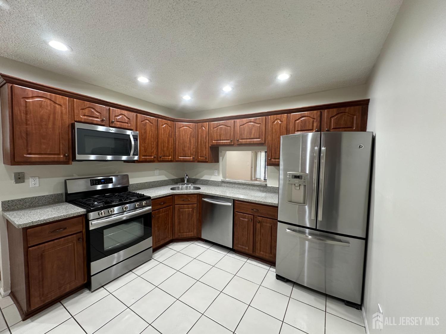 a kitchen with stainless steel appliances granite countertop a refrigerator stove a sink dishwasher and microwave