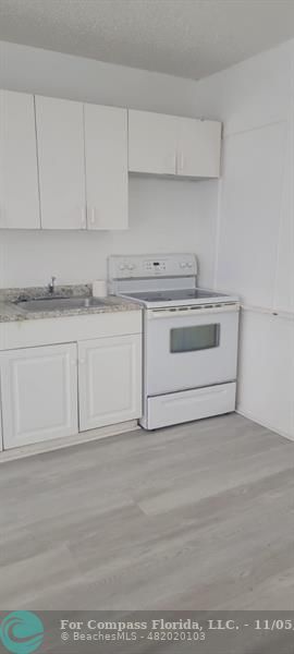 a white kitchen with granite countertop white cabinets and a white stove