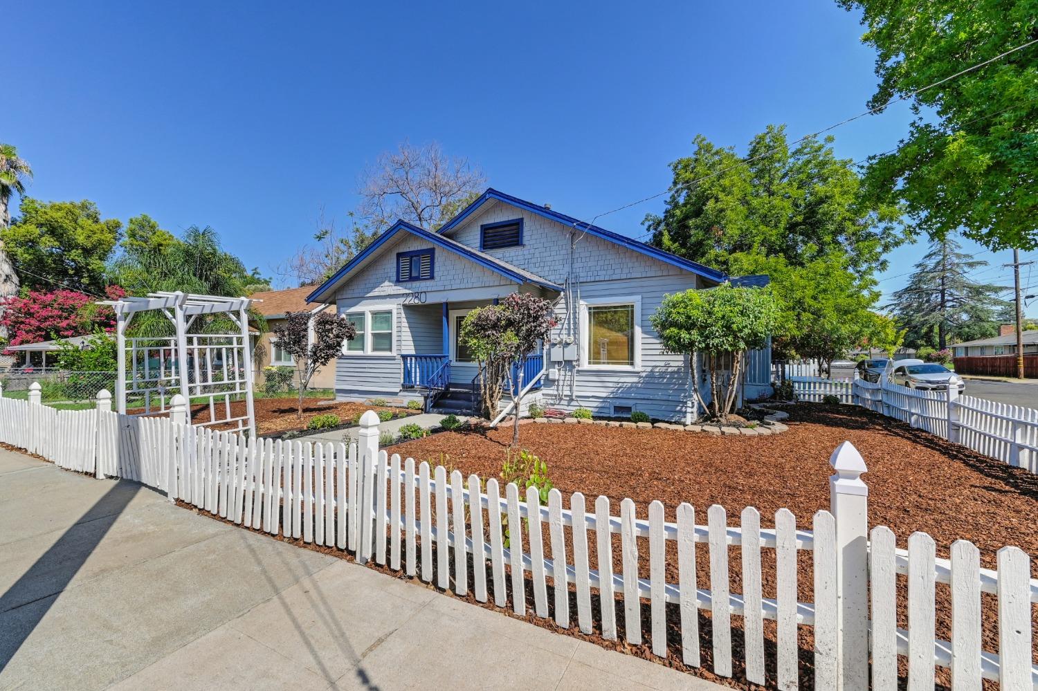 a view of a house with wooden fence next to a yard