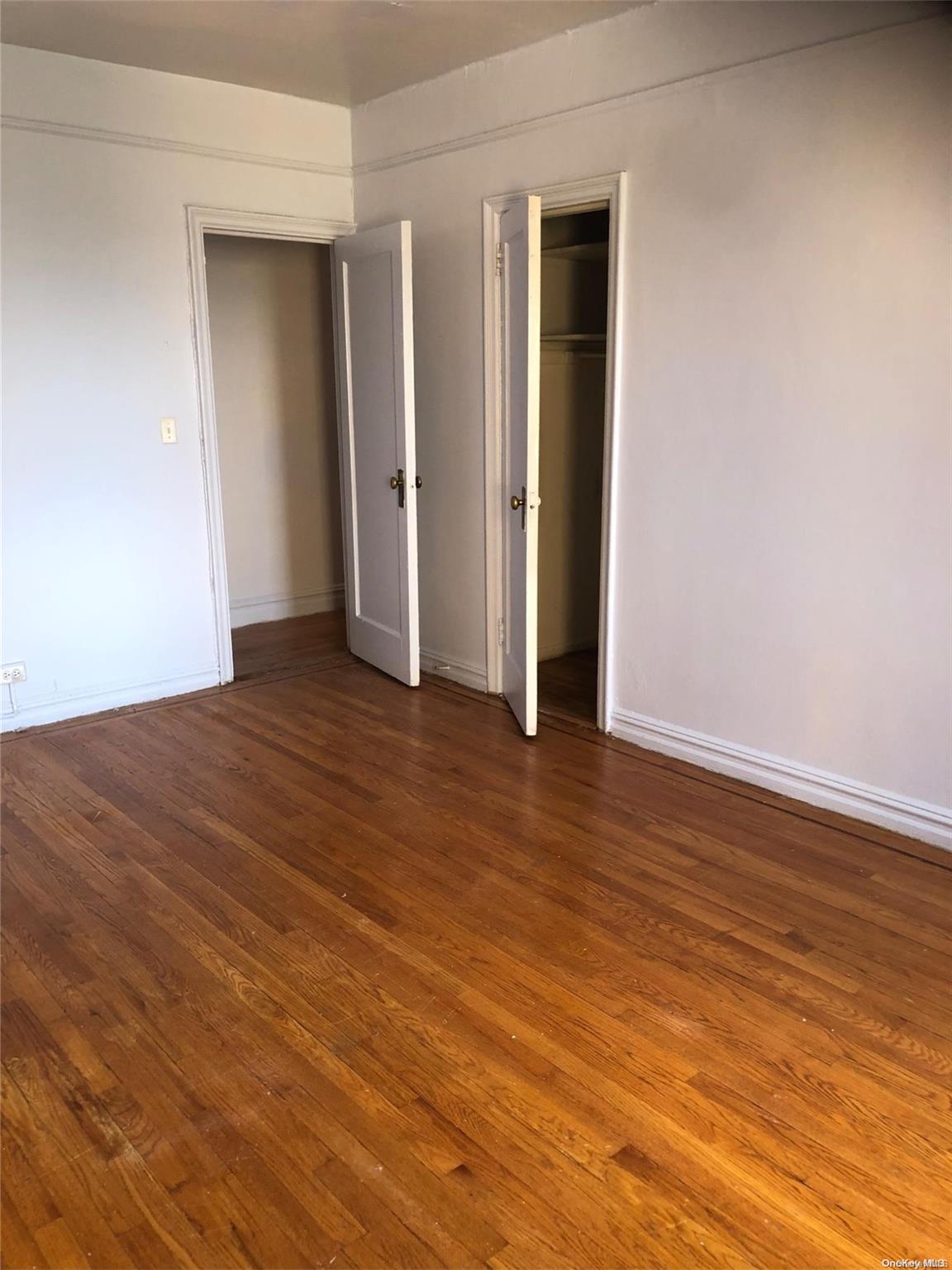 an empty room with wooden floor and closet