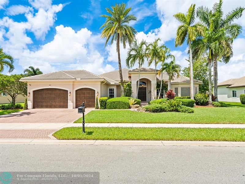 a front view of a house with a garden and palm trees