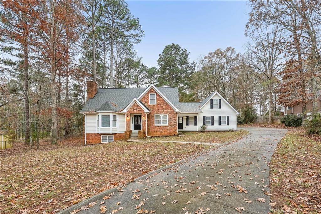 a front of a house with a yard and large tree