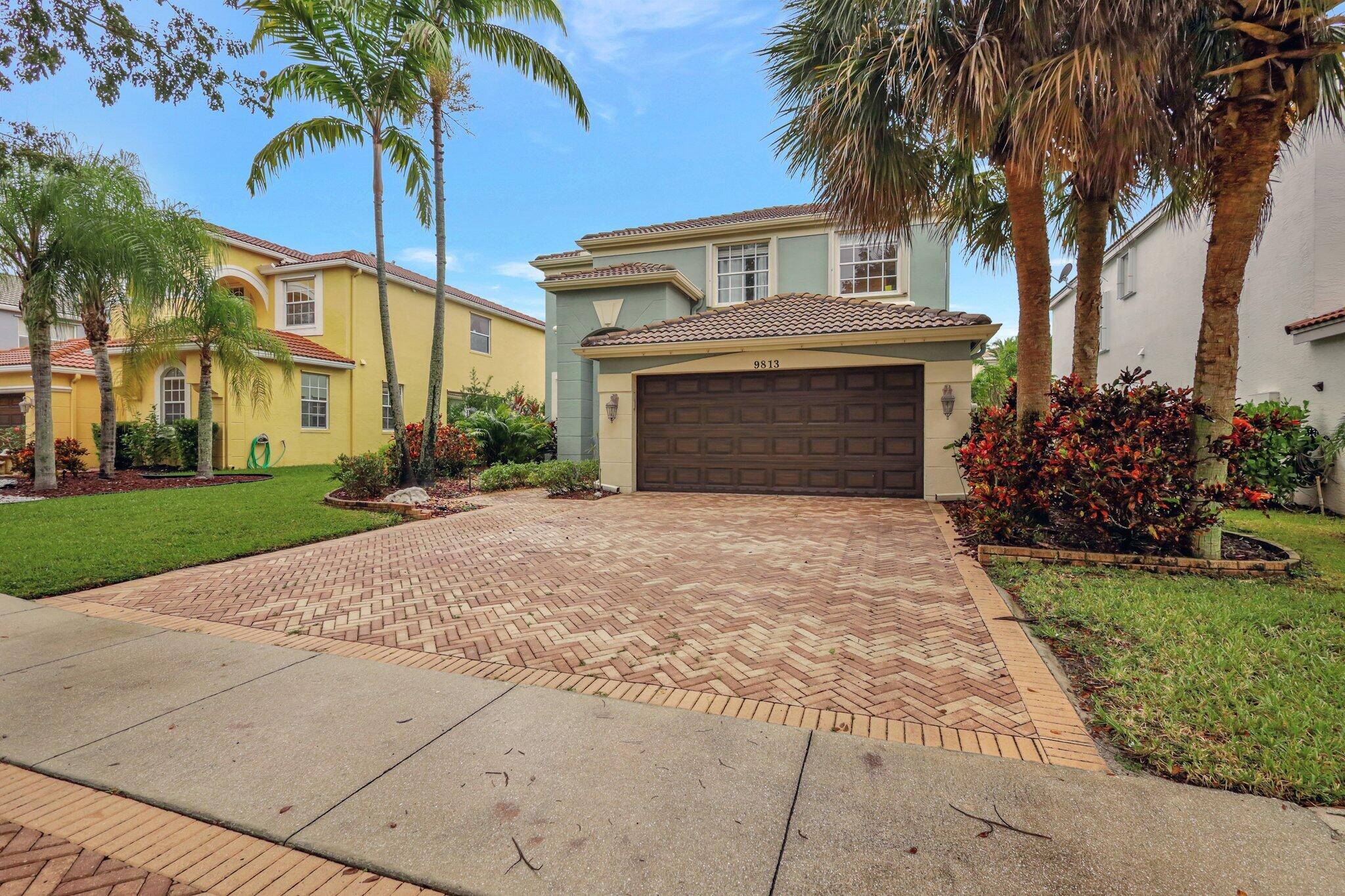 a front view of a house with a garden and palm trees