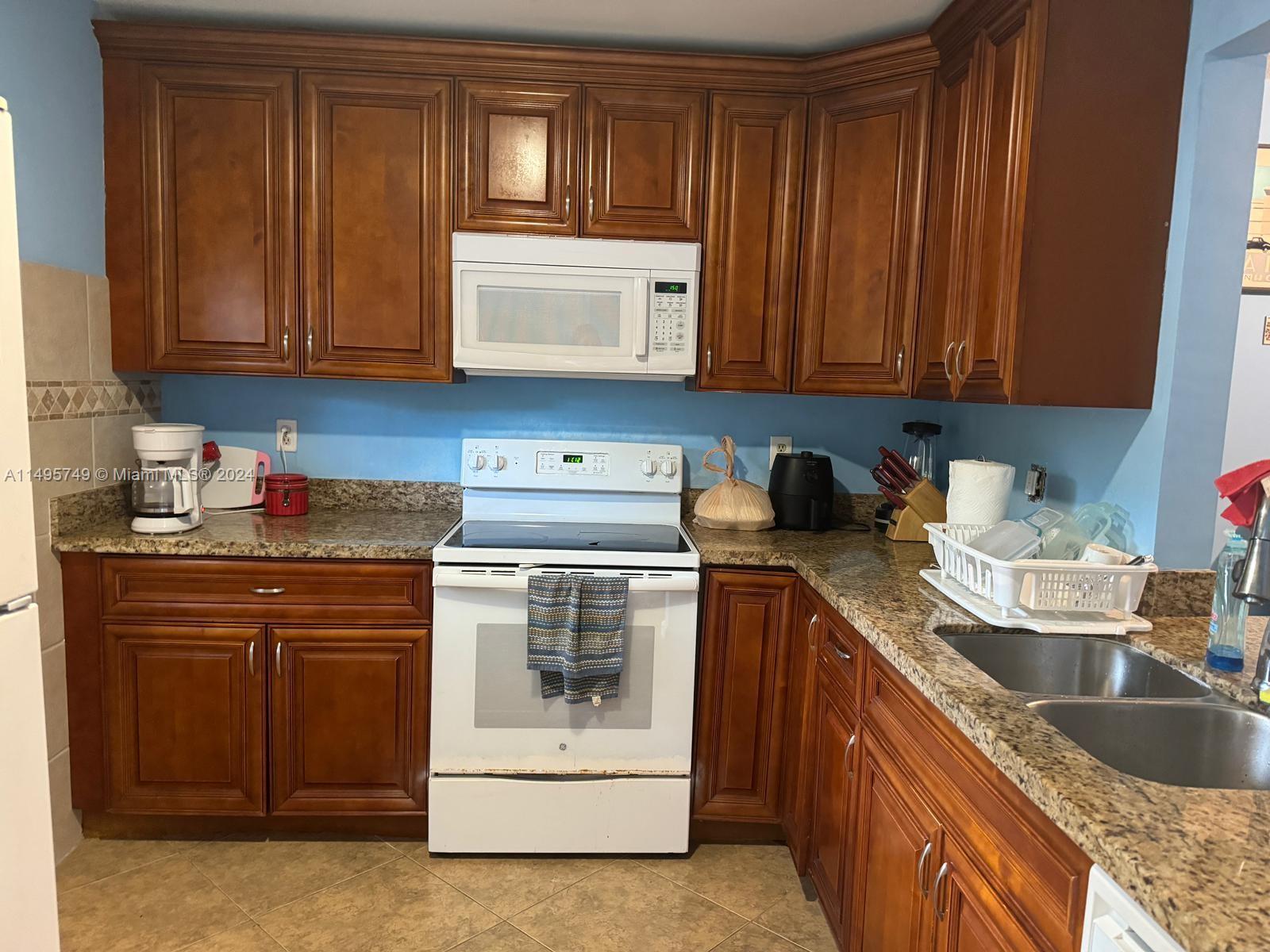 a kitchen with granite countertop wood cabinets stainless steel appliances and a sink