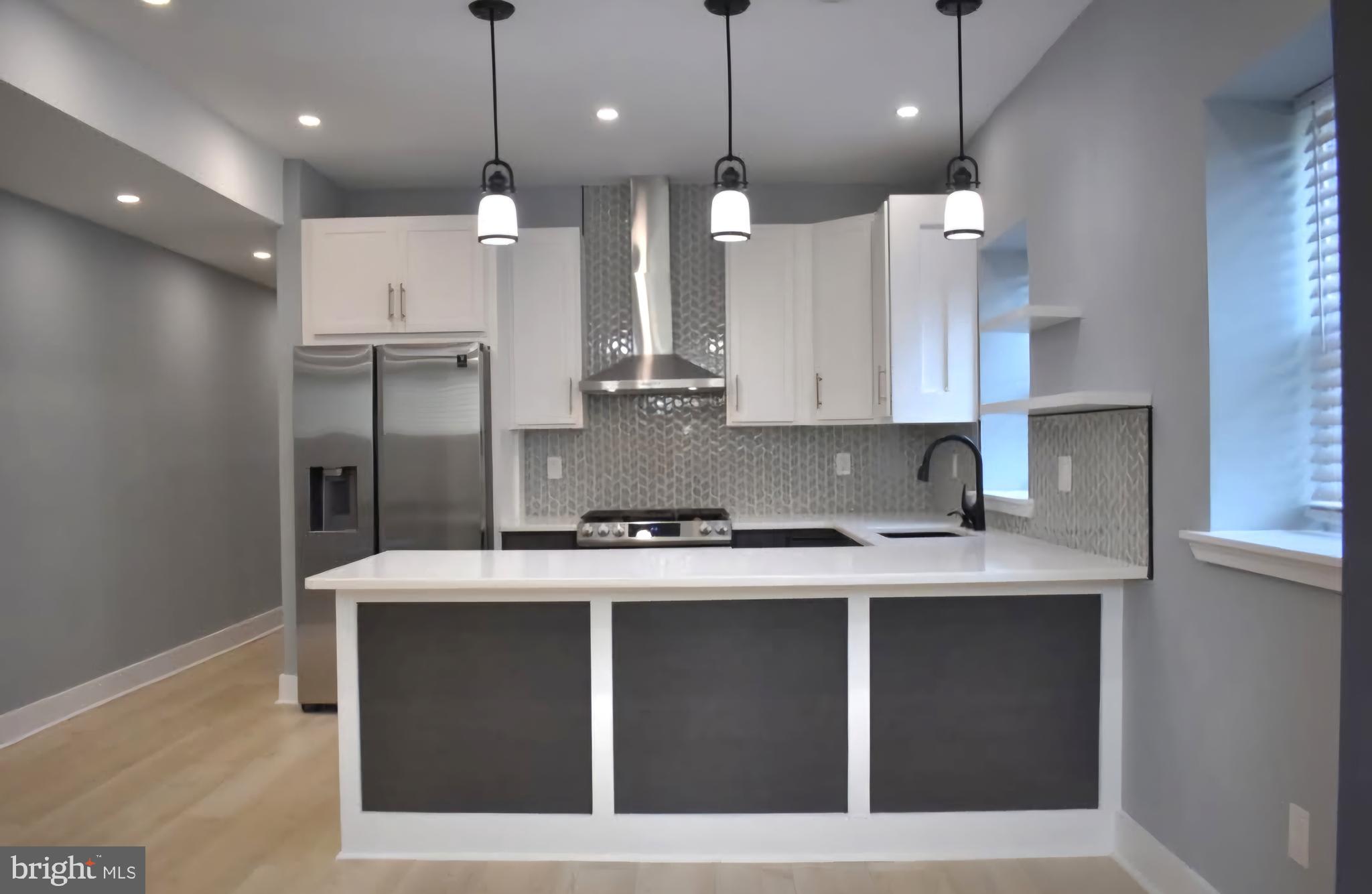 a kitchen with kitchen island a refrigerator and a sink