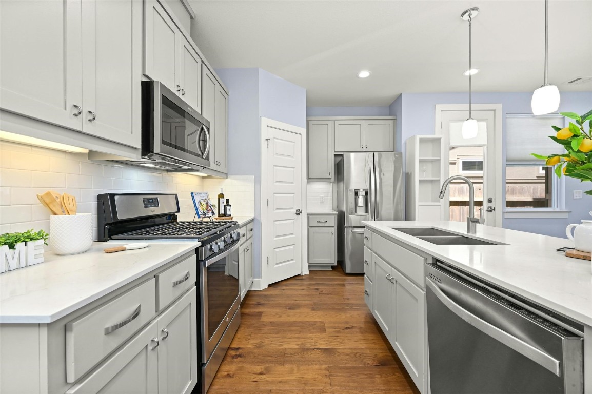 a kitchen with stainless steel appliances granite countertop a sink a stove and a refrigerator