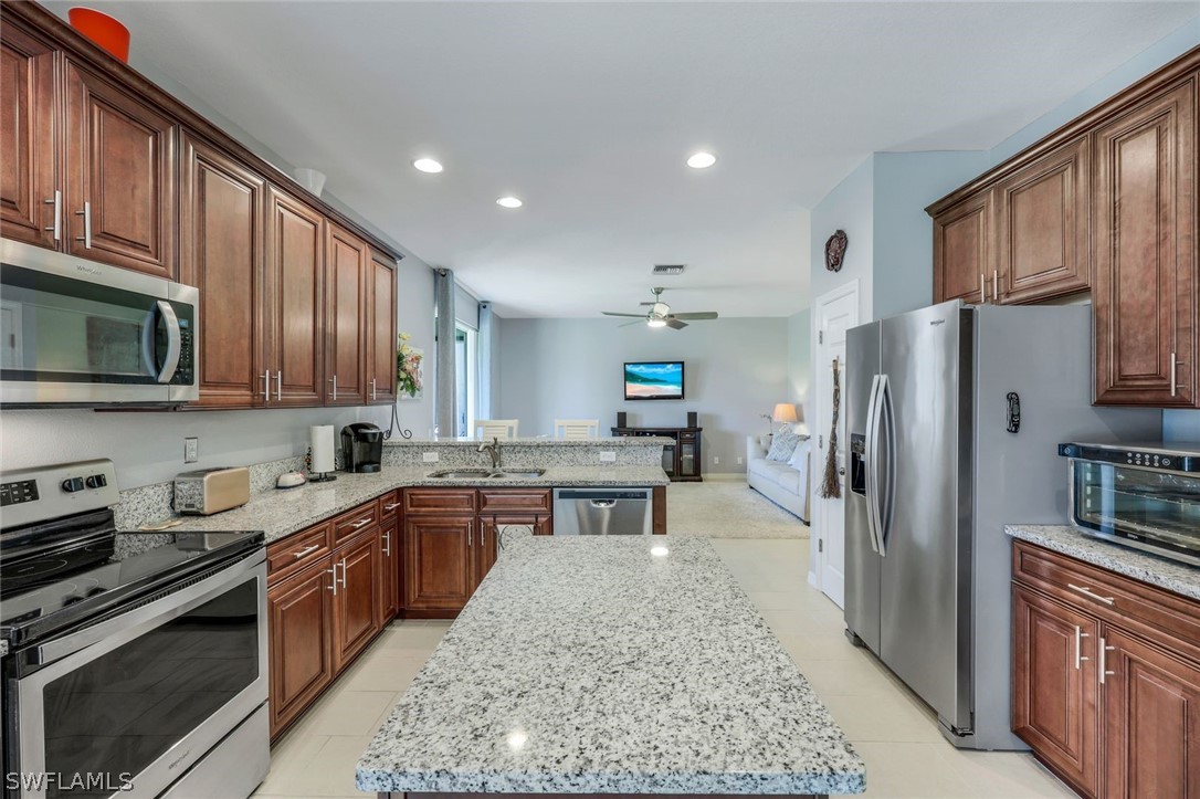 a large kitchen with stainless steel appliances granite countertop a refrigerator stove microwave and sink