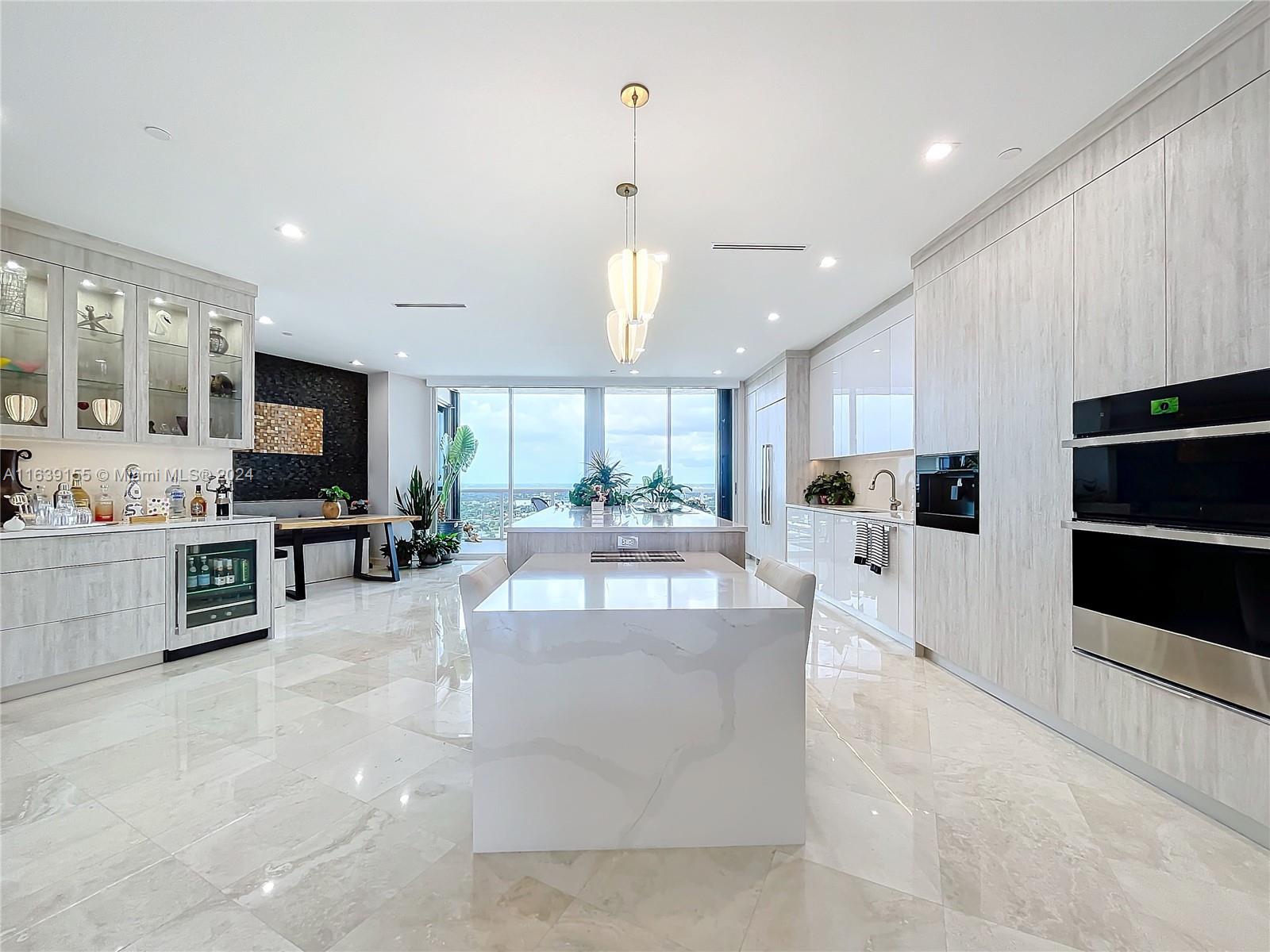 a large white kitchen with kitchen island a counter top space a sink stainless steel appliances and cabinets