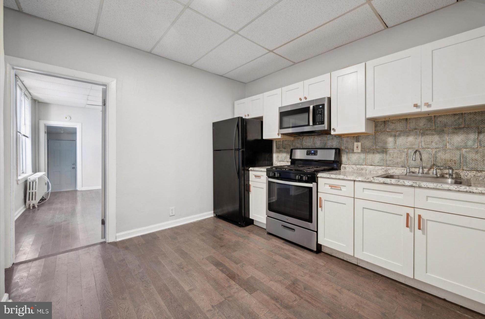 a kitchen with granite countertop a refrigerator and a stove top oven