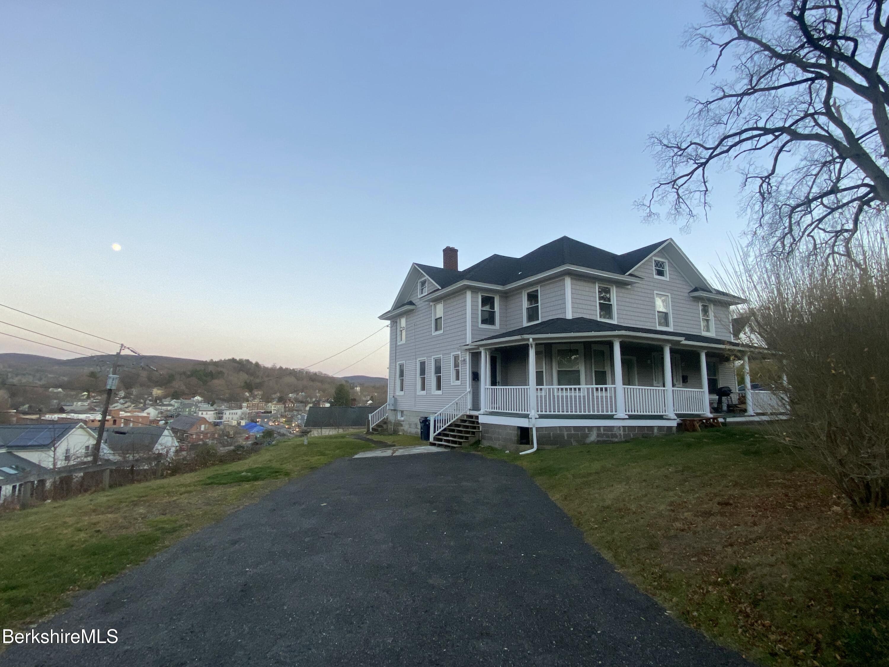 a view of a white house with a big yard and large trees