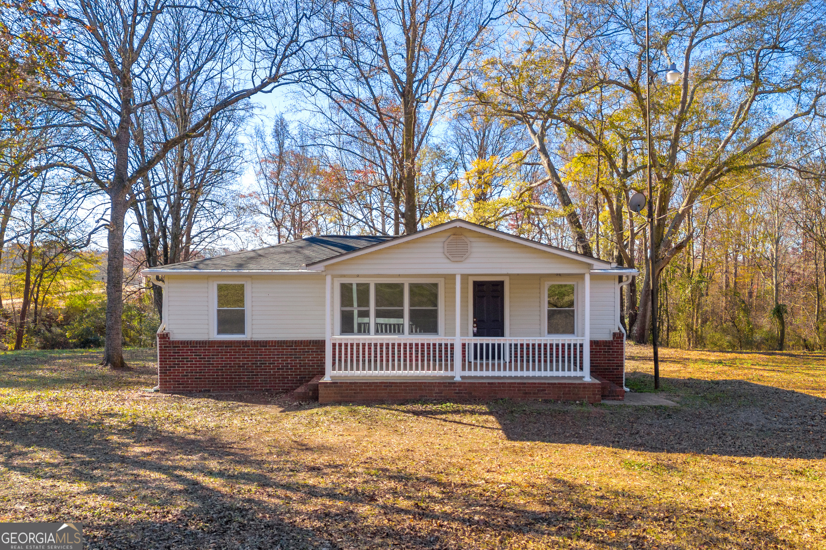 a front view of a house with a yard covered with trees