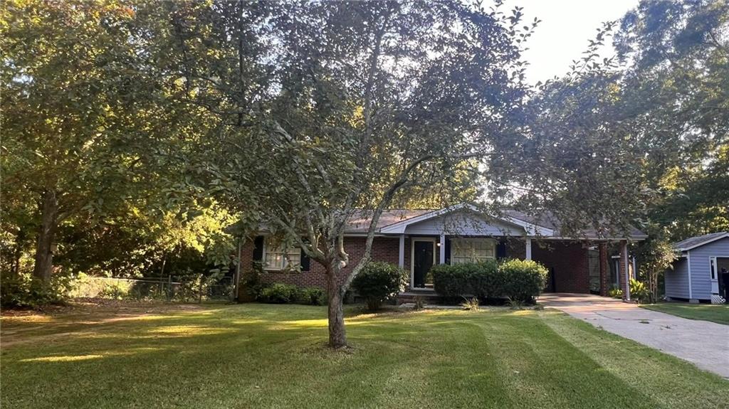 a front view of a house with a garden and trees