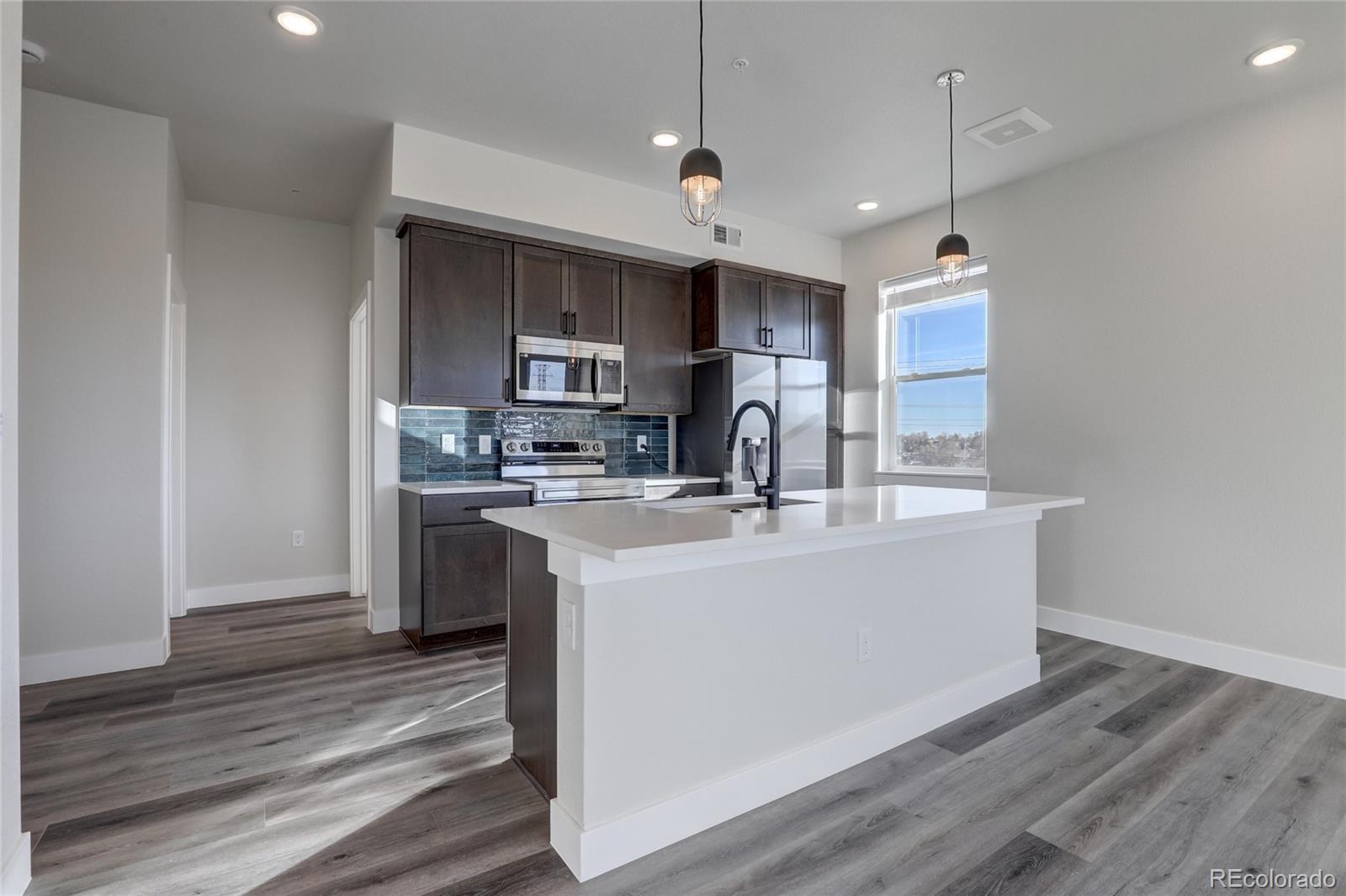 a kitchen with kitchen island a sink stainless steel appliances and wooden floor