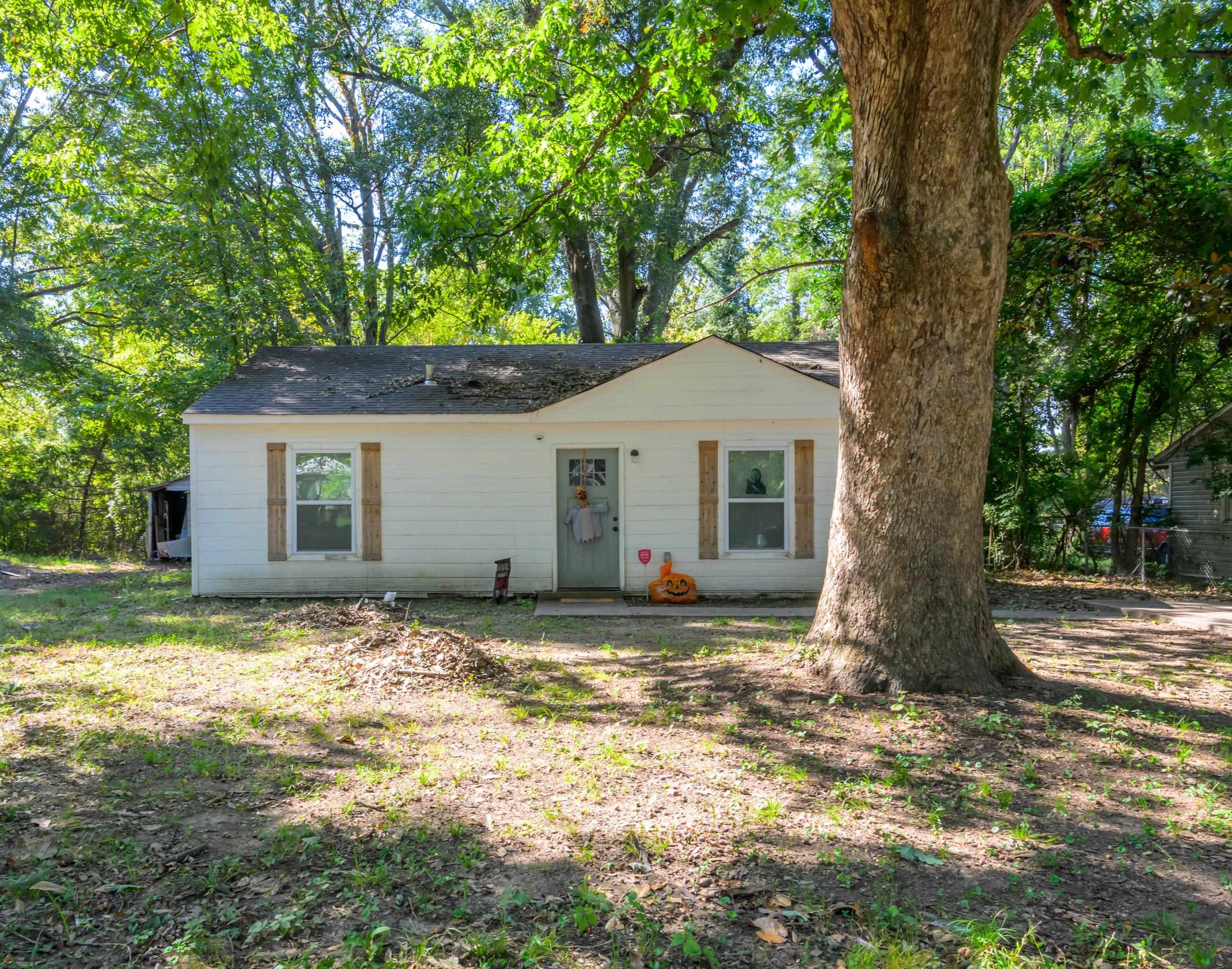 a view of a house with a yard and large tree