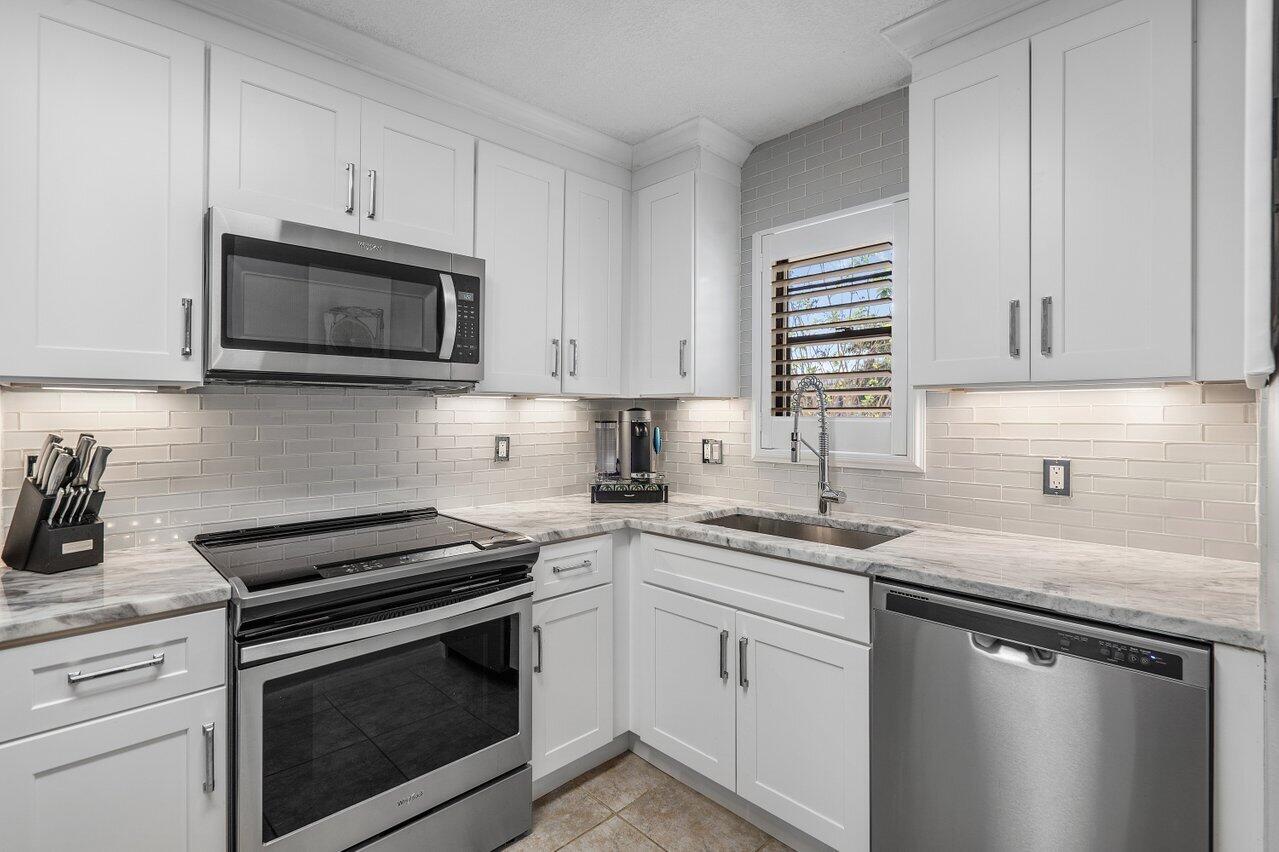 a kitchen with granite countertop white cabinets sink and stainless steel appliances