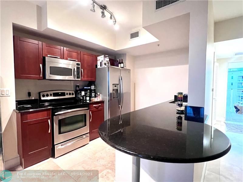 a kitchen with stainless steel appliances granite countertop a sink and a refrigerator