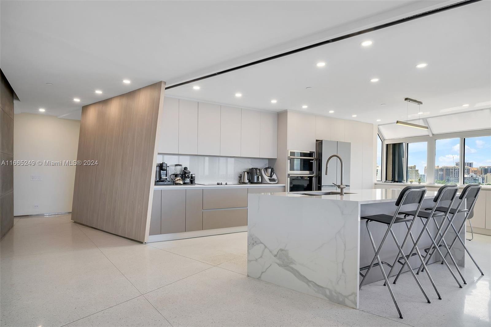 a view of a kitchen with kitchen island white cabinets and stainless steel appliances