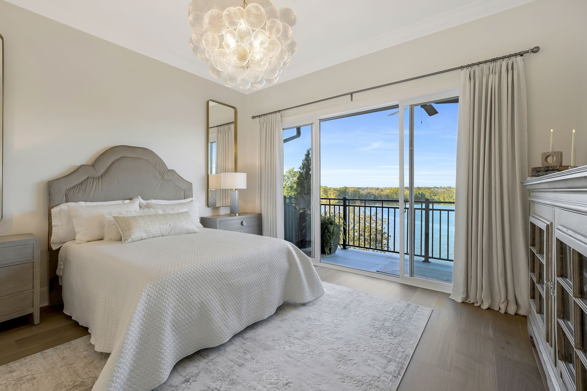 a bedroom with a large bed and a chandelier next to a window