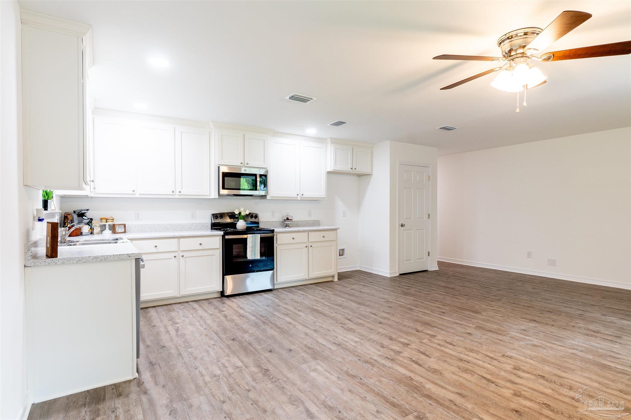 a kitchen with granite countertop a stove top oven a sink cabinets and wooden floor