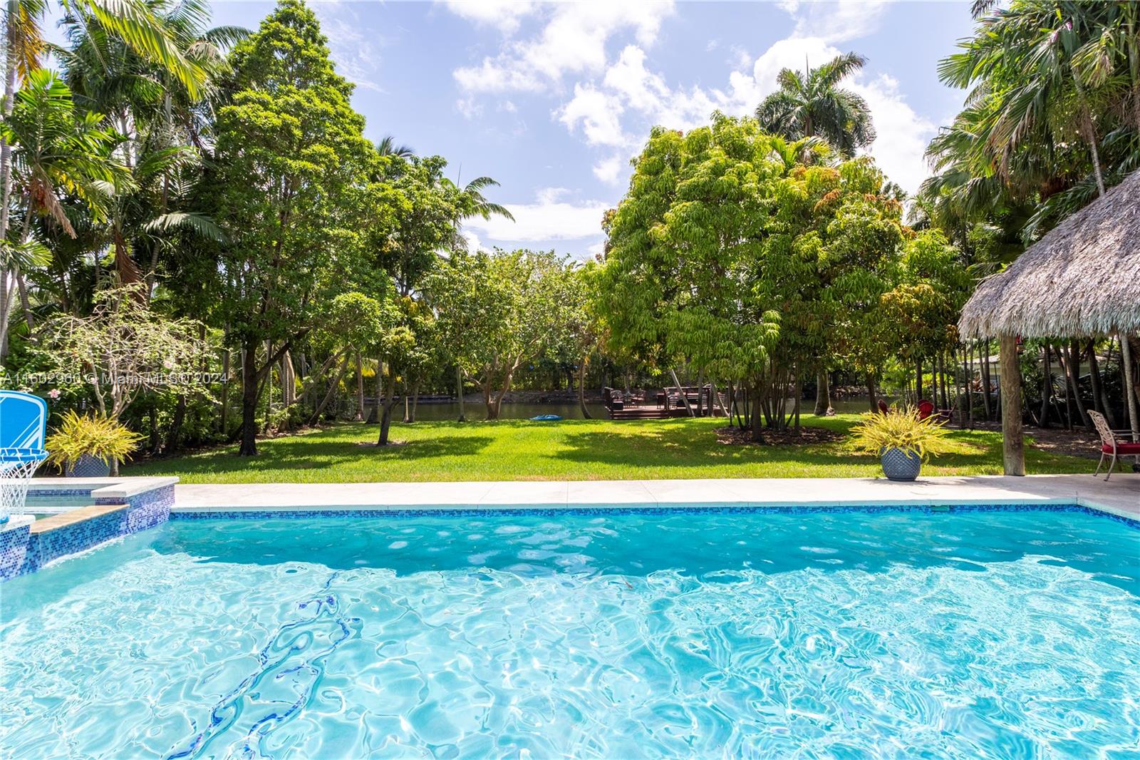 a view of pool with lawn chairs and large trees