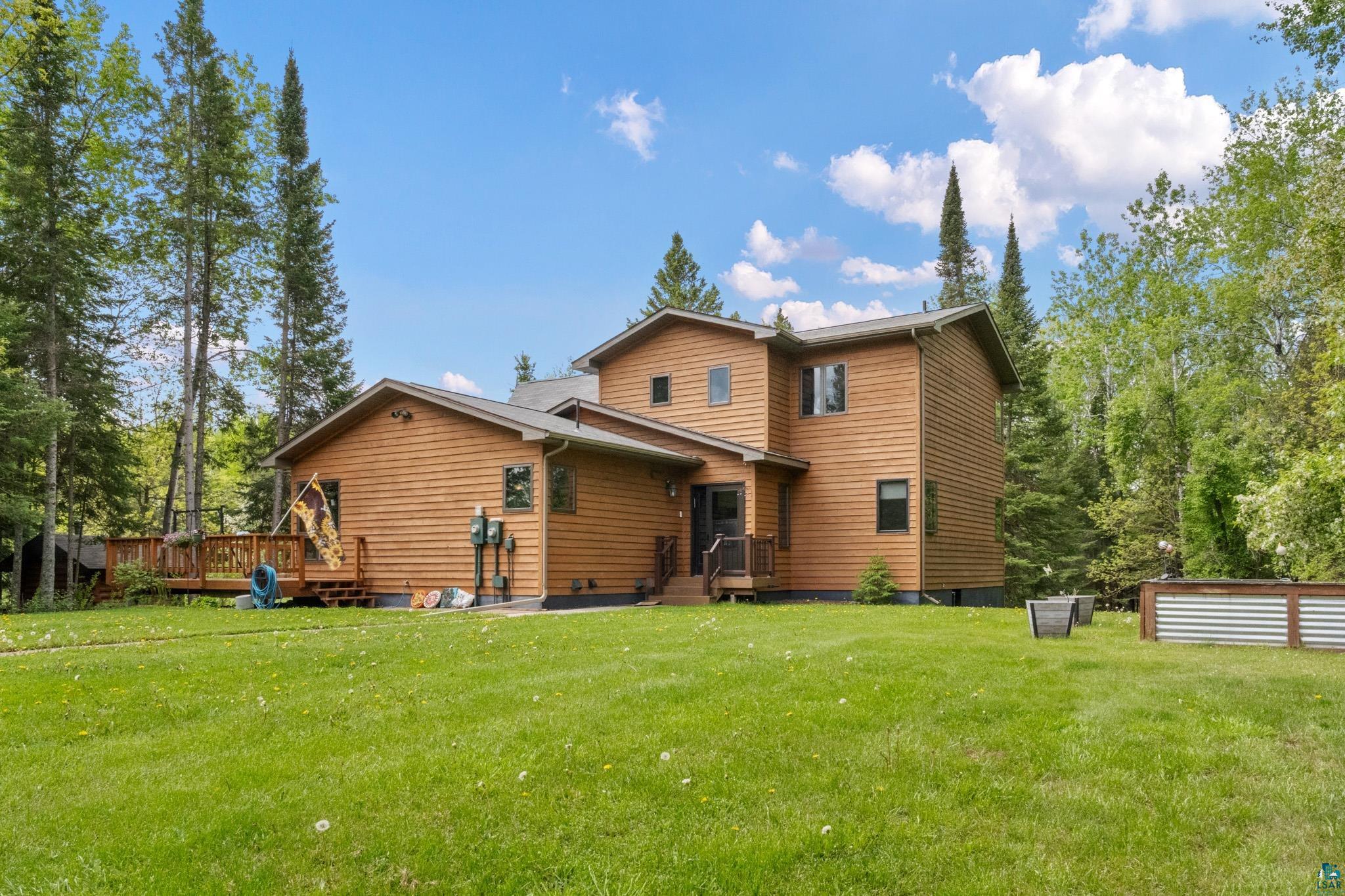 Back of house with a wooden deck and a lawn