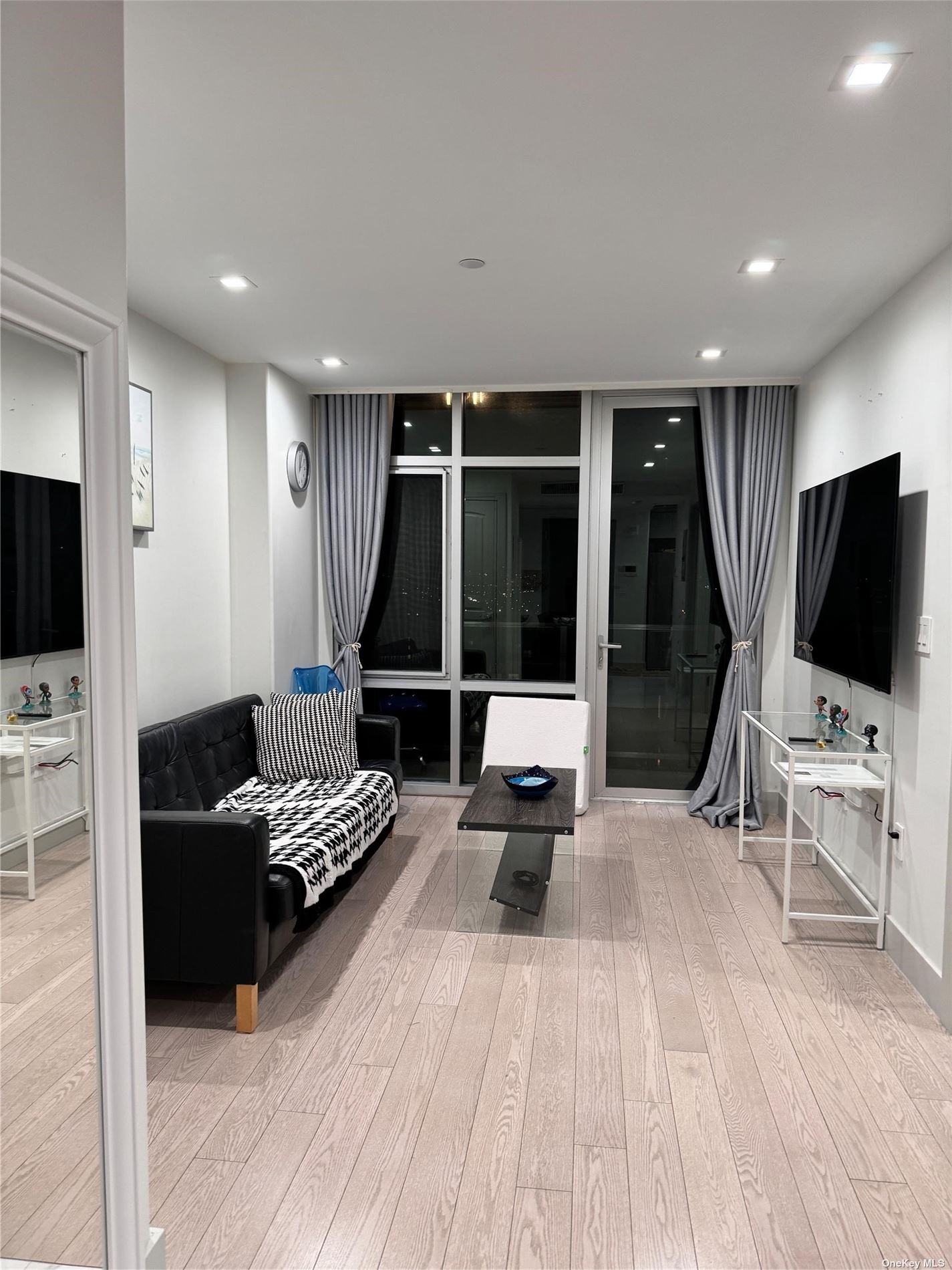 a living room with furniture a flat screen tv and a floor to ceiling window