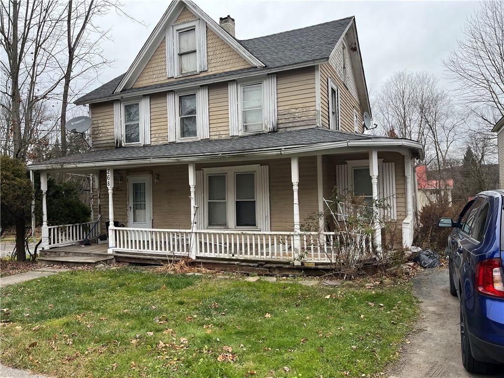 Farmhouse featuring covered porch and a front lawn