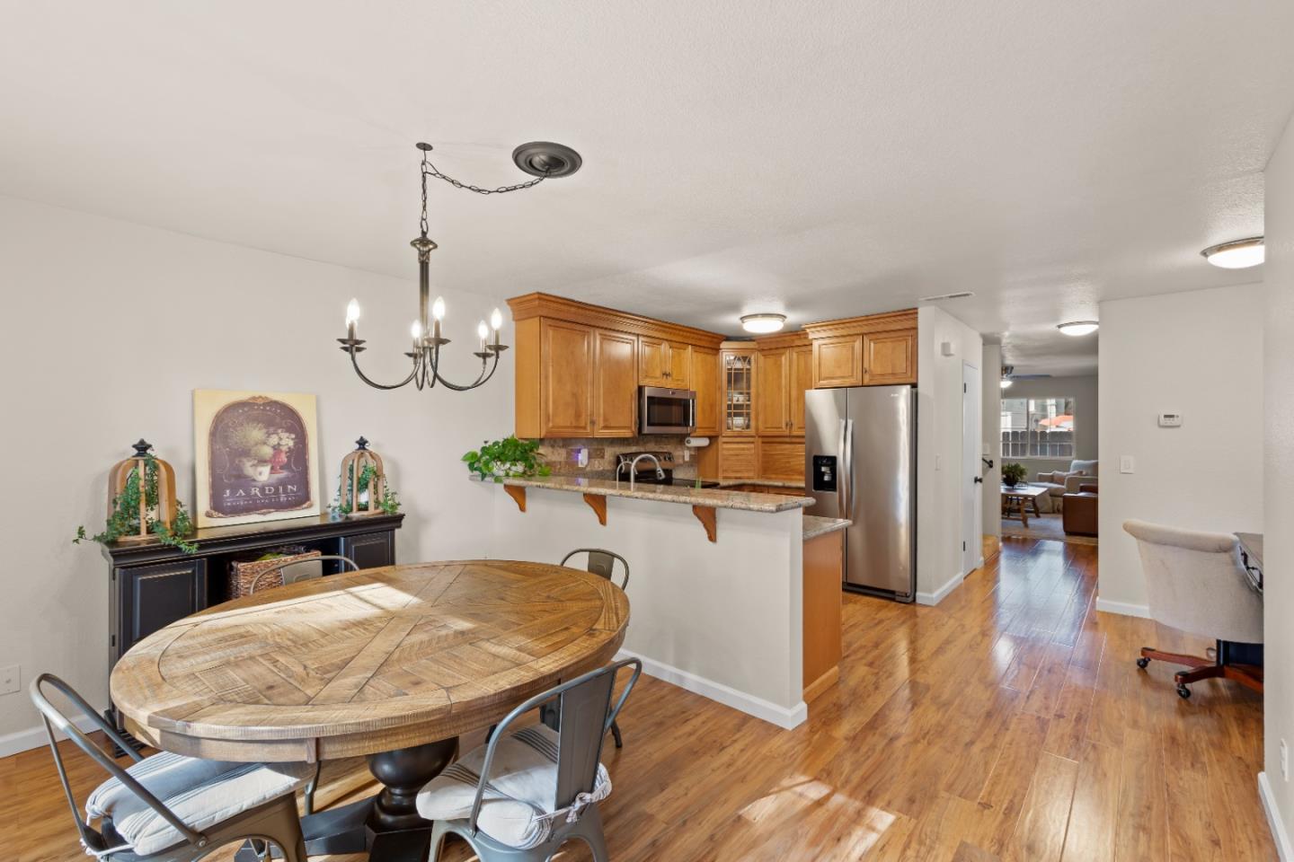 a kitchen with stainless steel appliances kitchen island granite countertop a refrigerator a stove a sink dishwasher with a dining table and chairs with wooden floor