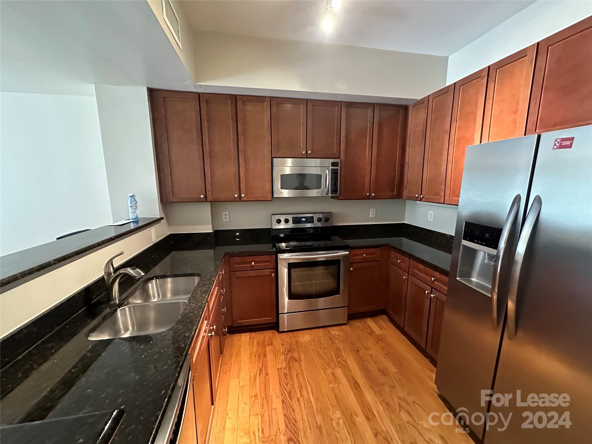 a kitchen with granite countertop a refrigerator and a stove top oven