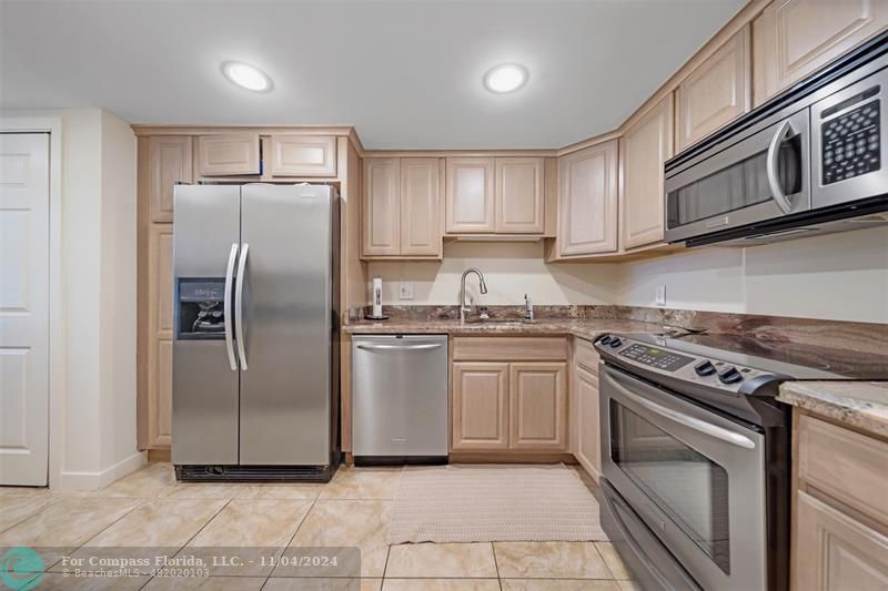 a kitchen with granite countertop a refrigerator sink and cabinets