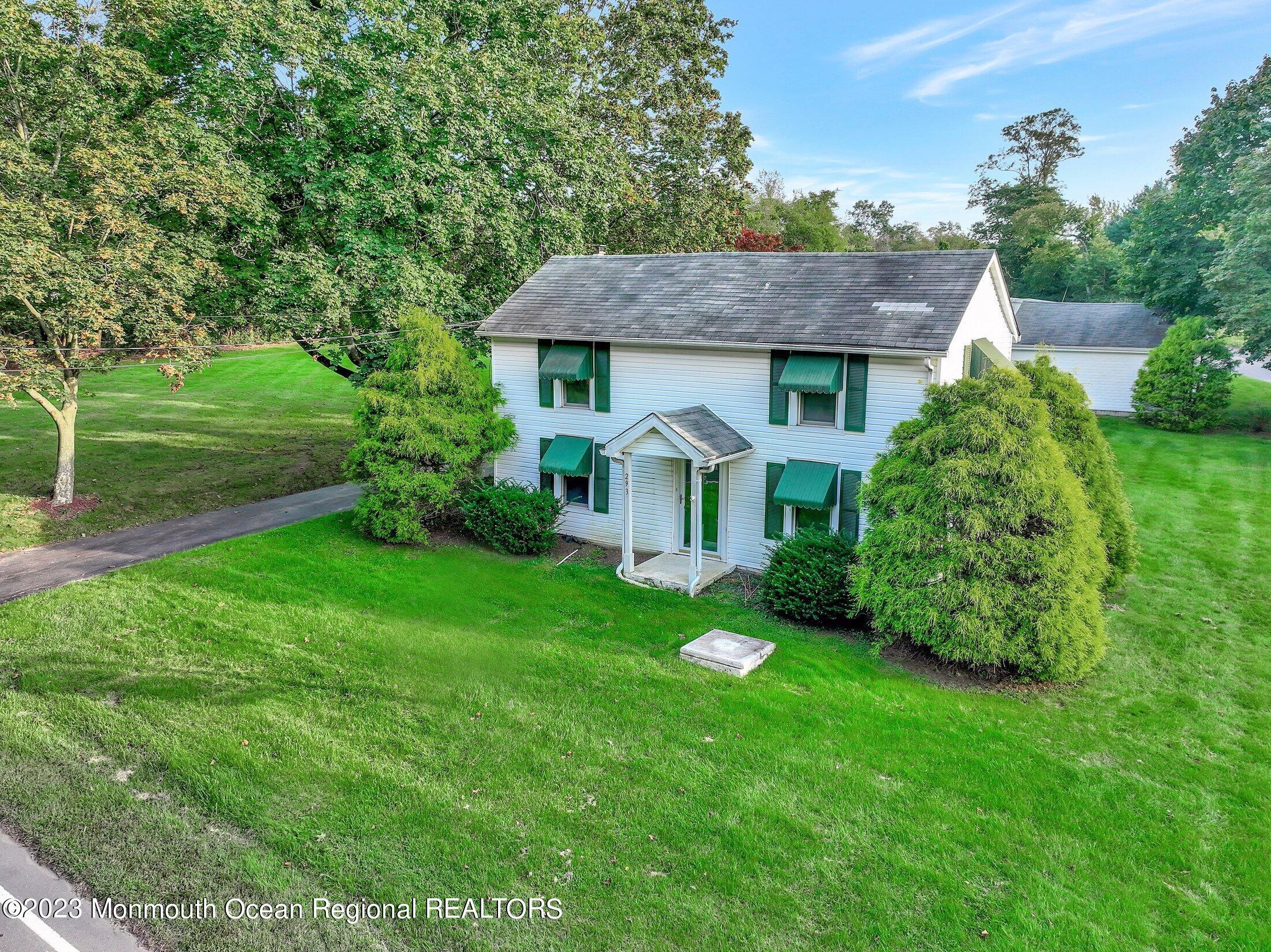 a view of a house with a big yard potted plants and large tree