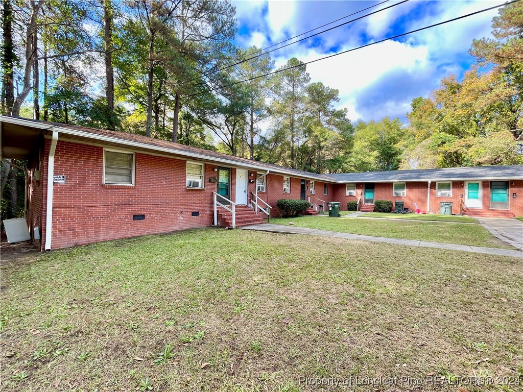 a front view of house with yard and trees in the background