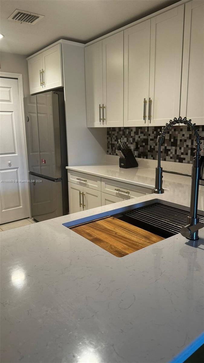 a kitchen with stainless steel appliances a refrigerator a sink and white cabinets