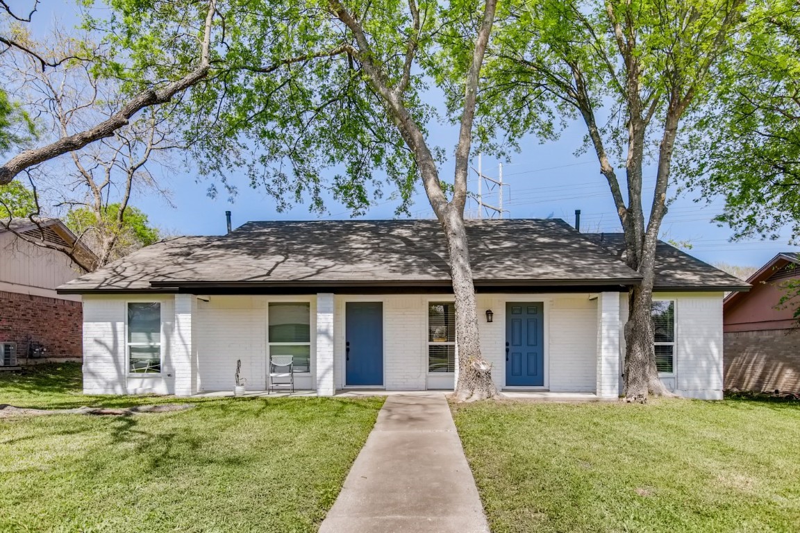 a front view of a house with a garden and trees