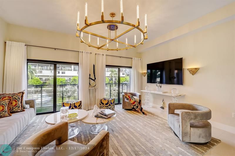 a living room with furniture a flat screen tv and a floor to ceiling window