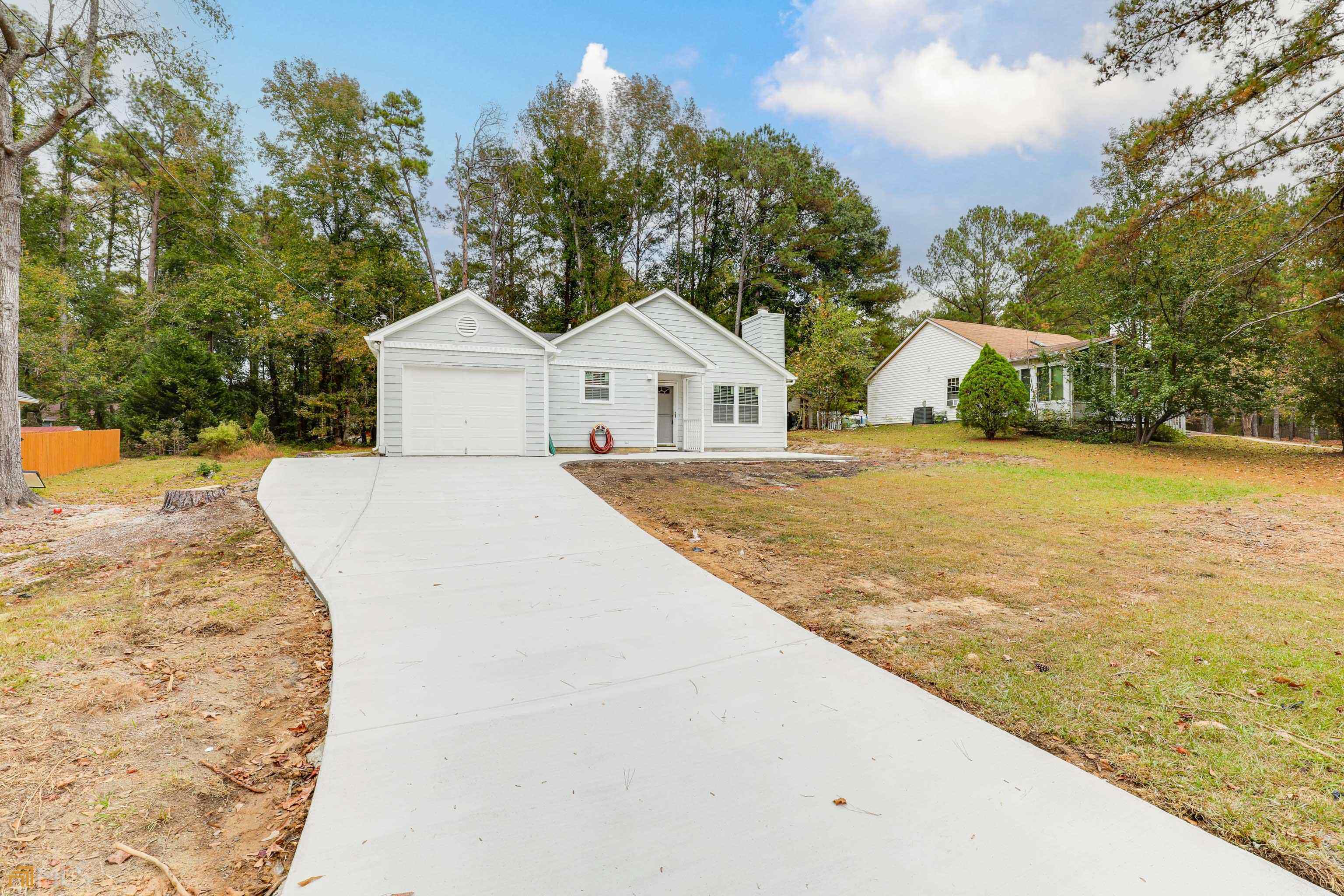 a view of house with yard and trees in the background