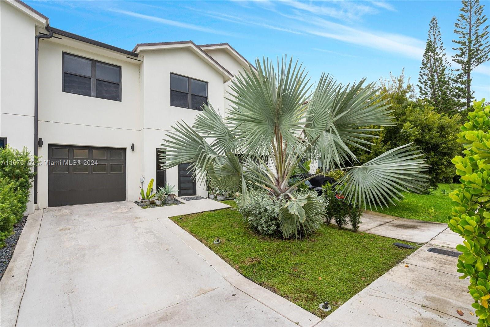 a front view of a house with a garden and palm trees