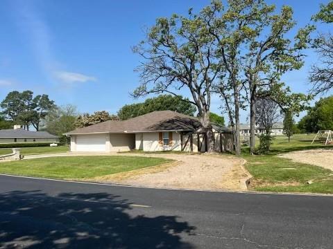 a view of a house with a yard and a large tree