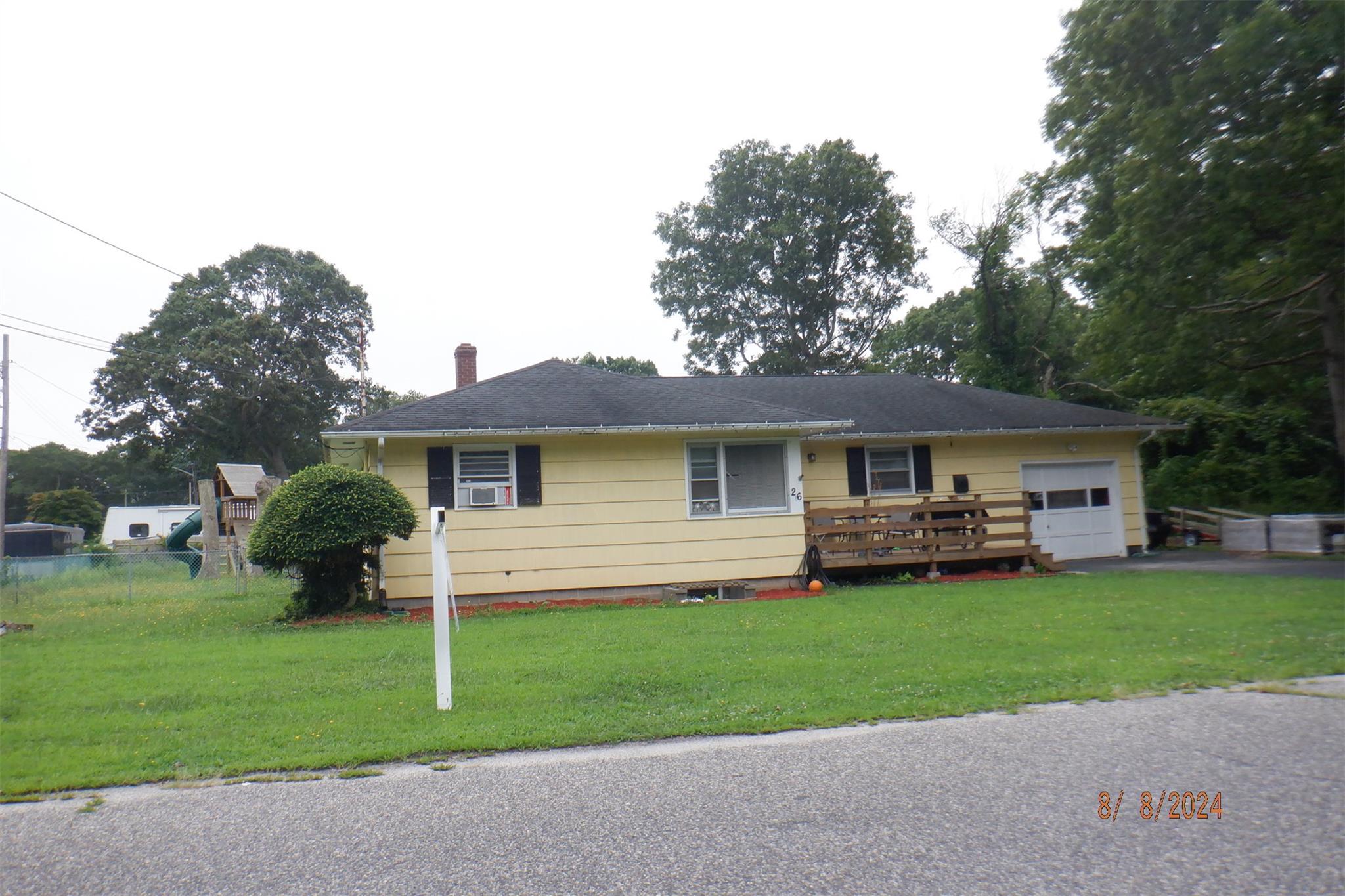 View of front of home featuring cooling unit, a deck, and a front yard