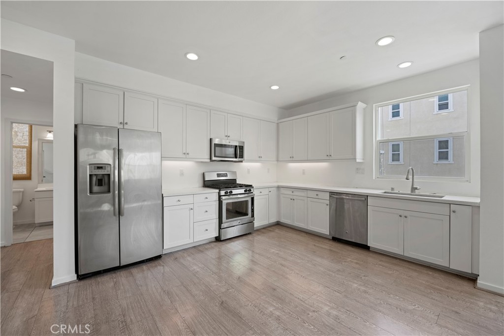 a large kitchen with cabinets wooden floor and stainless steel appliances