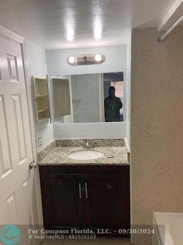 a bathroom with a granite countertop sink and a mirror