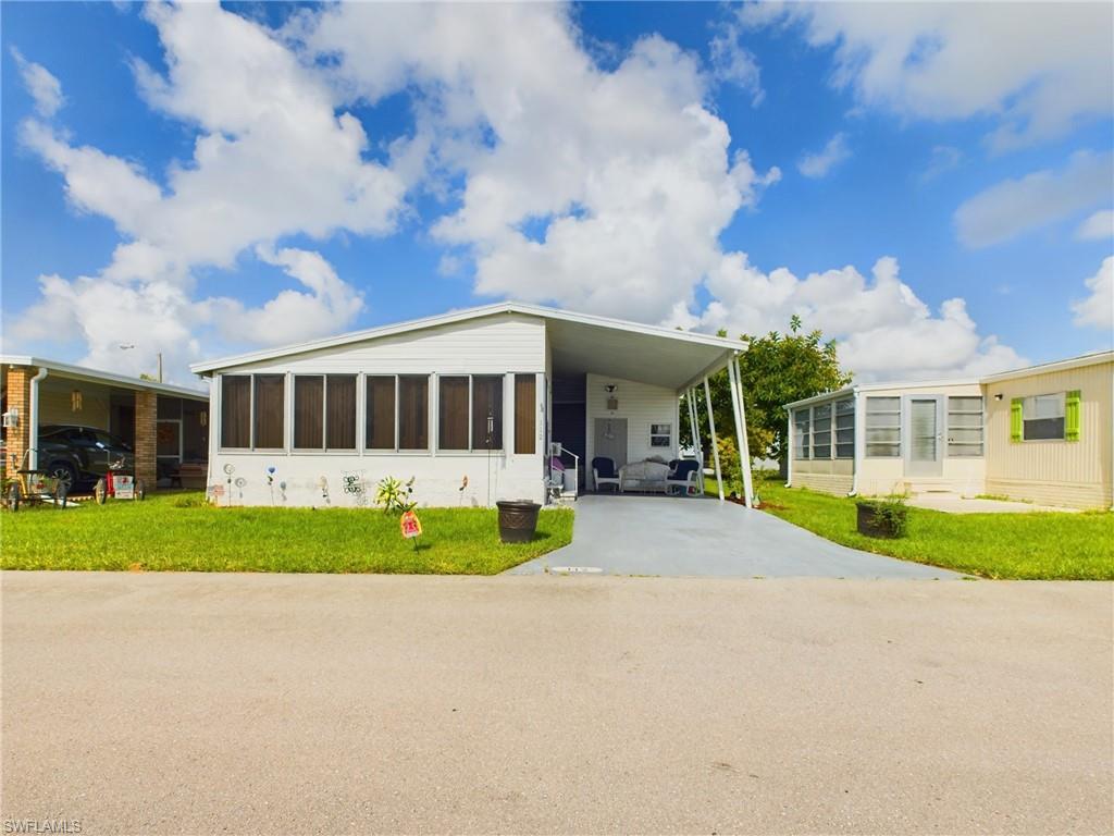 Manufactured / mobile home featuring a sunroom, a front yard, and a carport