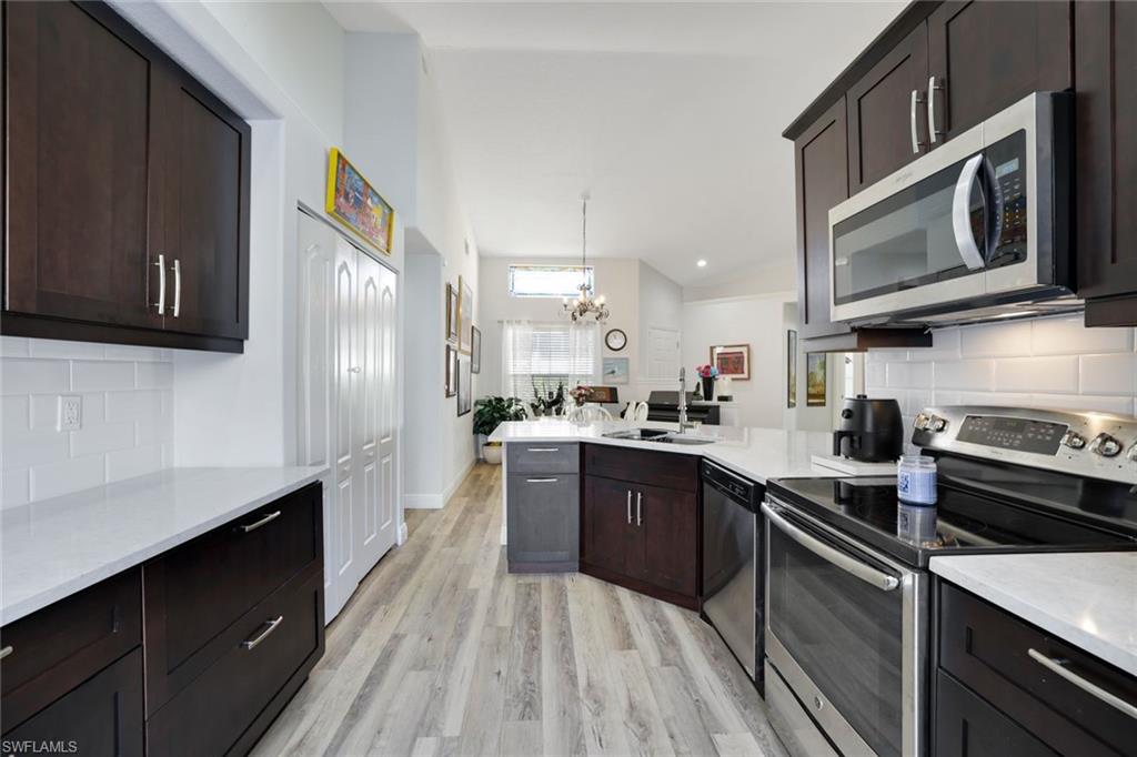 Kitchen featuring backsplash, a chandelier, stainless steel appliances, and light wood-type flooring