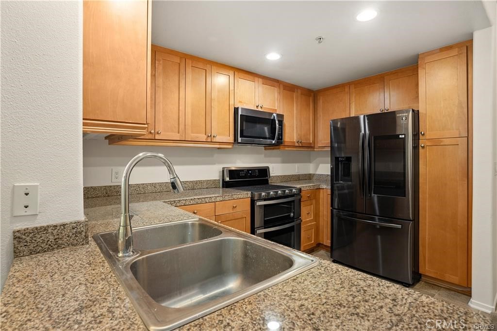 a kitchen with stainless steel appliances granite countertop a refrigerator a stove a sink and a microwave