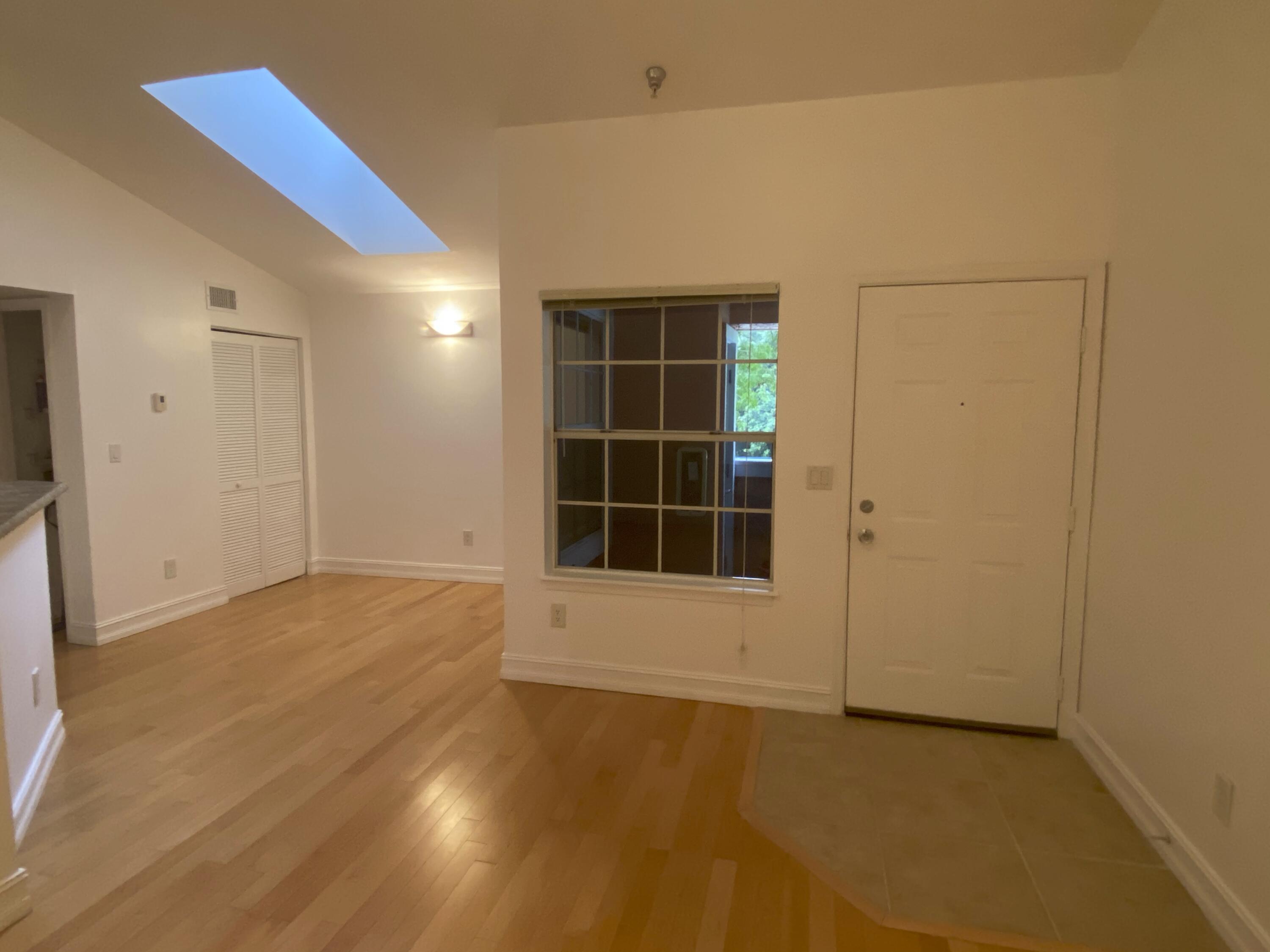 a view of an empty room with a window and wooden floor