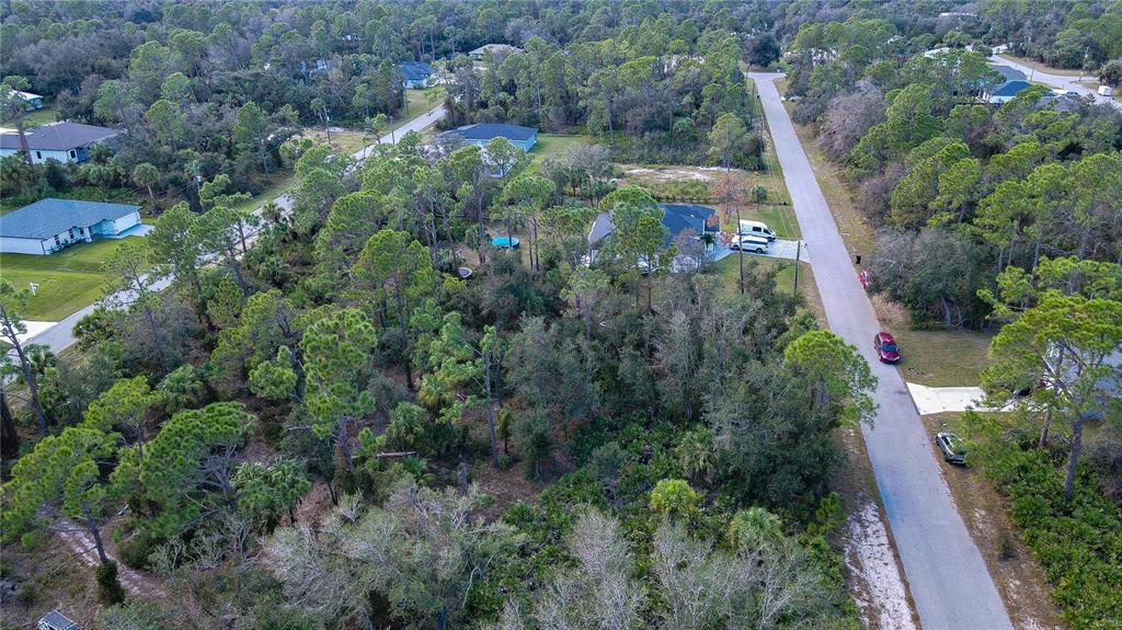 an aerial view of residential house with outdoor space and trees all around