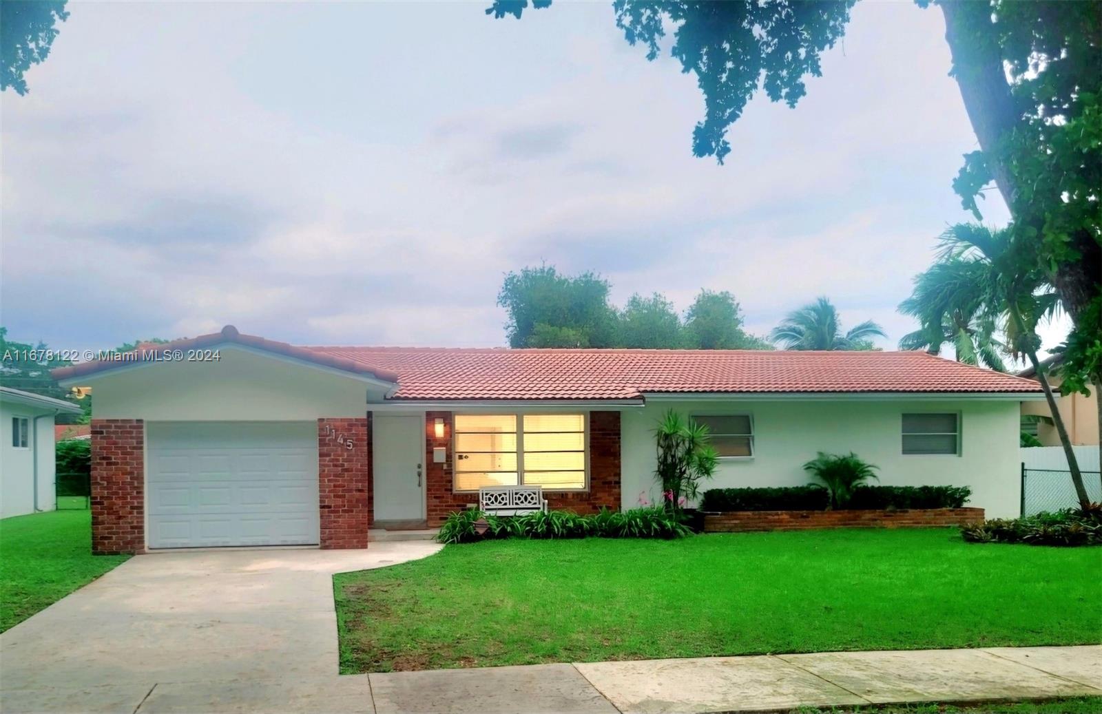 a front view of a house with a garden and trees