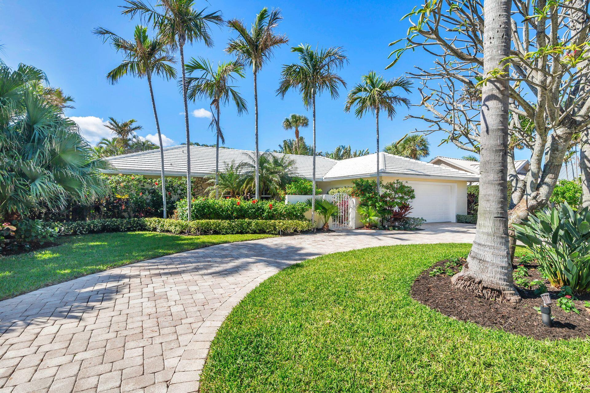 a view of a house with a yard and palm trees