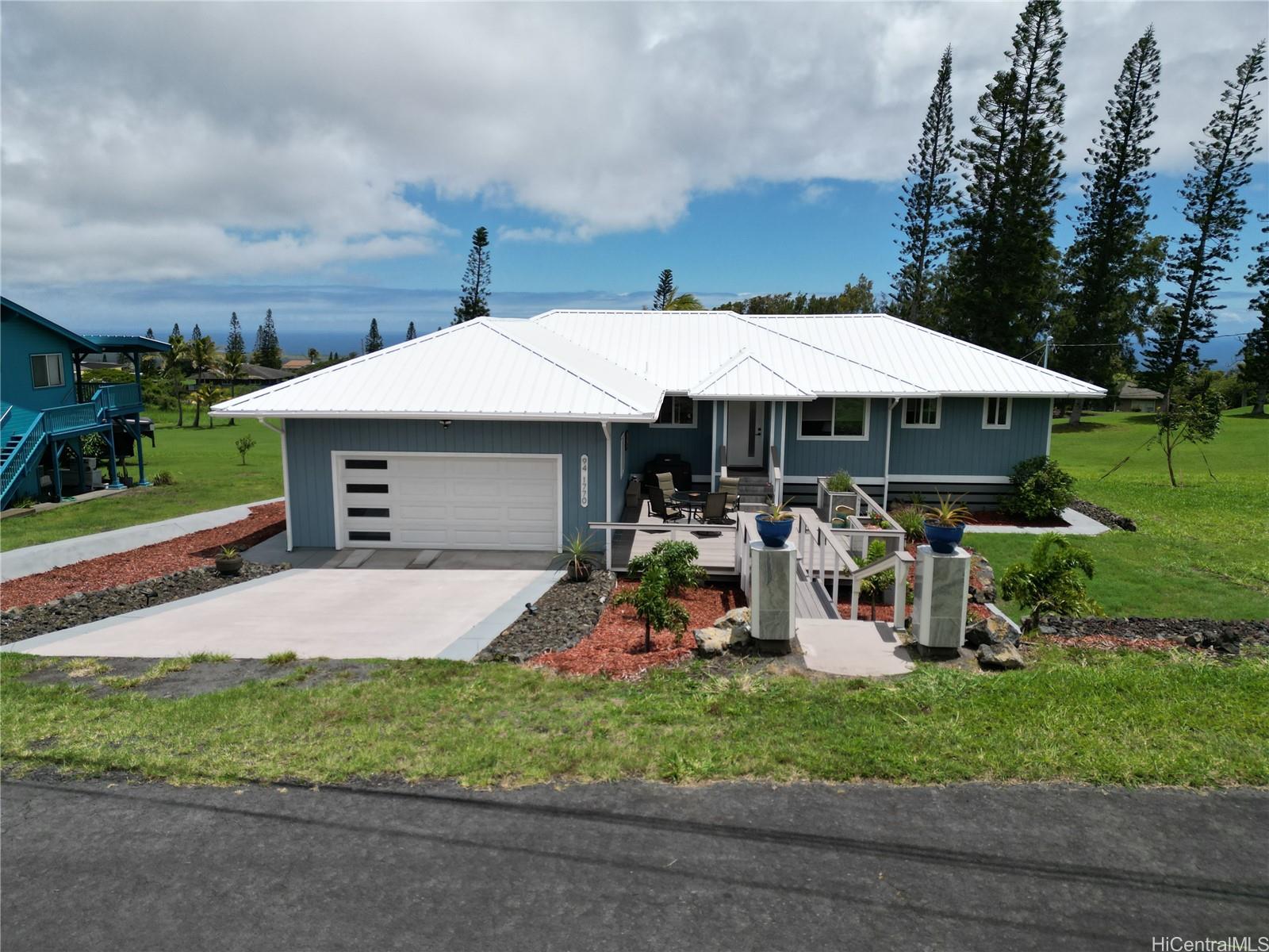 Front of the home with a closed garage door, blue sky and clouds.