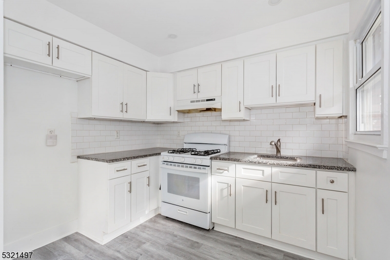 a kitchen with granite countertop white cabinets and white appliances